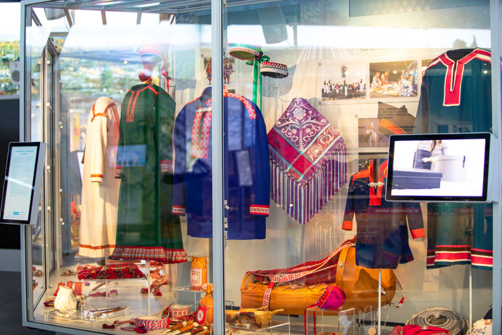 Colorful Sámi clothing and cultural objects displayed inside Siida museum.